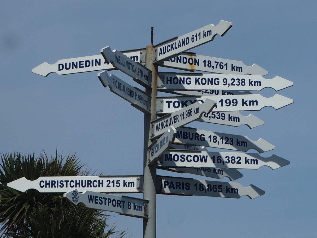 Sign post with places around the world from the end of Cape Foulwind Walkway