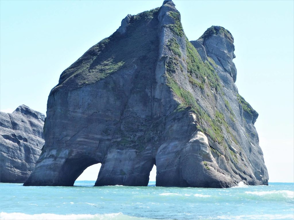 Large arch rock formation off the beach at Whakariki Beach